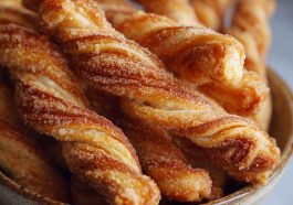 Golden-brown cinnamon twists with flaky layers, dusted with sugar and cinnamon, served on a rustic tray with coffee.