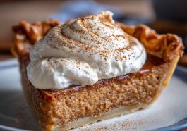 A golden-baked apple butter pie with a smooth filling, warm spices, and flaky crust, topped with whipped cream and cinnamon.