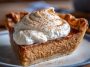 A golden-baked apple butter pie with a smooth filling, warm spices, and flaky crust, topped with whipped cream and cinnamon.