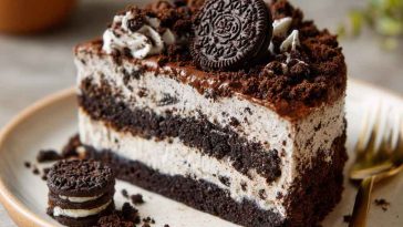 OREO dirt cake layered with crushed cookies, creamy pudding, and whipped topping, served in a glass dish with gummy worms for decoration.