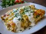 A baking dish filled with golden chicken enchiladas smothered in sour cream white sauce, topped with melted cheese and fresh cilantro.