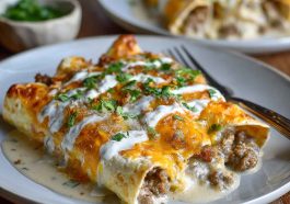 Southern breakfast enchiladas stuffed with eggs, cheese, and sausage, topped with creamy sausage gravy and baked until golden.