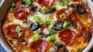 Low carb crustless pizza bowl filled with melted cheese, pepperoni, sausage, and fresh vegetables.