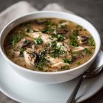 Clean chicken mushroom soup with tender chicken pieces, earthy mushrooms, carrots, and herbs simmered in a clear broth.