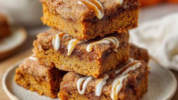 Delicious pumpkin snickerdoodle blondies cut into squares, topped with a cinnamon sugar crust and served in portions.