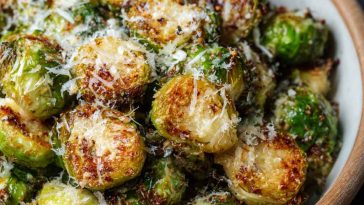 Crispy roasted Brussels sprouts topped with melted Parmesan cheese on a baking tray