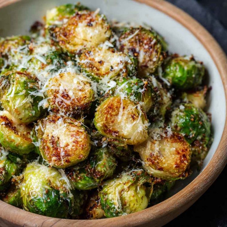 Crispy roasted Brussels sprouts topped with melted Parmesan cheese on a baking tray