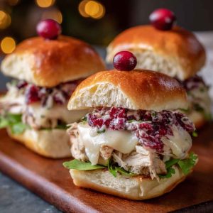 Mini Havarti cranberry turkey sliders with melted cheese, cranberry sauce, and golden slider buns served on a platter.