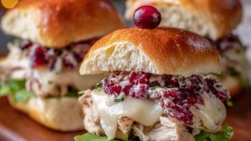 Mini Havarti cranberry turkey sliders with melted cheese, cranberry sauce, and golden slider buns served on a platter.