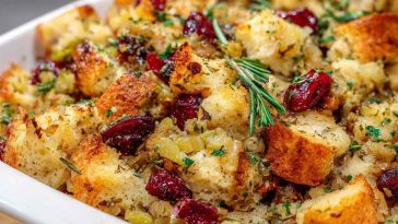Homemade Thanksgiving stuffing baked golden in a casserole dish, filled with bread cubes, herbs, celery, and onions.