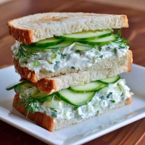Fresh cucumber salad sandwiches layered with creamy spread, crisp cucumbers, and herbs, served on soft bread slices.