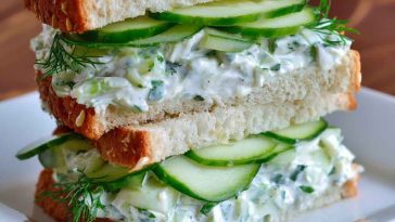 Fresh cucumber salad sandwiches layered with creamy spread, crisp cucumbers, and herbs, served on soft bread slices.