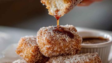 Crispy angel cake churro bites coated in cinnamon sugar, served in a bowl with dipping sauce.