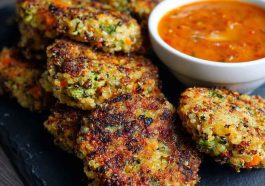 Crunchy quinoa veggie patties stacked on a plate, golden brown with fresh herbs and served with dipping sauce.