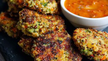 Crunchy quinoa veggie patties stacked on a plate, golden brown with fresh herbs and served with dipping sauce.