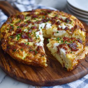 A golden-baked frittata filled with crispy bacon, tender Yukon Gold potatoes, and melted Gruyère cheese, garnished with scallions.