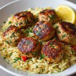 Greek chicken meatballs served over lemon orzo pasta, garnished with fresh herbs and feta cheese.