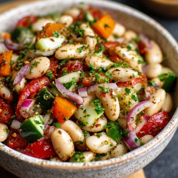 A vibrant bowl of marinated za’atar bean salad with white beans, cherry tomatoes, red onion, and fresh herbs.