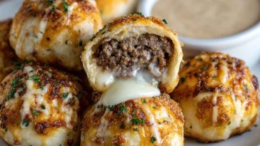 Golden cheeseburger bombs brushed with garlic butter and sprinkled with parmesan, served on a platter.
