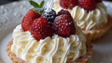 Mini tartlets filled with silky white chocolate mousse, topped with fresh berries and edible flowers on a porcelain tray.