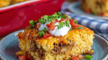 Loaded cornbread casserole baked golden in a dish, topped with melted cheese, corn, and savory mix-ins.