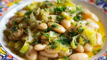 Creamy butter beans with sautéed leeks and herbs served in a rustic bowl with crusty bread.