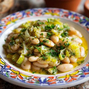 Creamy butter beans with sautéed leeks and herbs served in a rustic bowl with crusty bread.