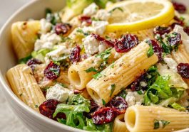 A vibrant bowl of rigatoni pasta tossed with feta cheese, dried cranberries, fresh herbs, and lemon vinaigrette.