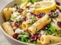 A vibrant bowl of rigatoni pasta tossed with feta cheese, dried cranberries, fresh herbs, and lemon vinaigrette.