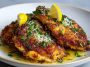 Golden crispy chicken cutlets topped with grated Pecorino and lemon zest on a serving plate.