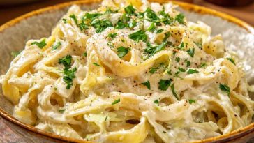 Creamy garlic Alfredo pasta with tender cabbage, topped with parmesan cheese and served in a rustic bowl.
