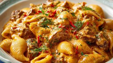 Creamy paprika steak shells in a skillet with tender steak pieces, pasta shells, and fresh herbs.