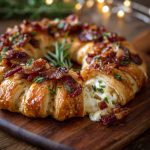 Golden crescent wreath filled with melted Brie, bacon, and herbs on a festive serving platter.