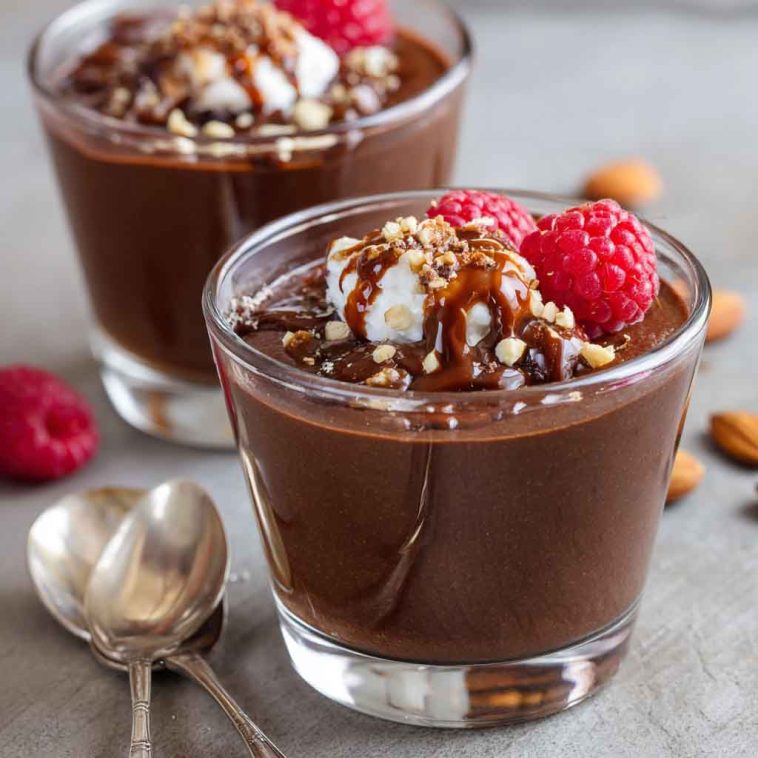 Glass jar of healthy chocolate pudding topped with berries and a sprinkle of cacao nibs.