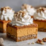 A tray of sweet potato pie bars with a golden crust, creamy spiced filling, and whipped cream topping.