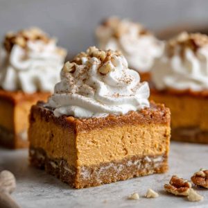 A tray of sweet potato pie bars with a golden crust, creamy spiced filling, and whipped cream topping.