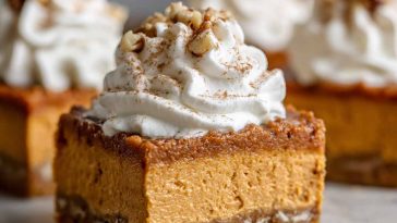 A tray of sweet potato pie bars with a golden crust, creamy spiced filling, and whipped cream topping.