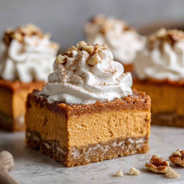 A tray of sweet potato pie bars with a golden crust, creamy spiced filling, and whipped cream topping.