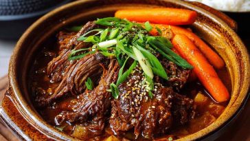 Tender Korean-style pot roast in a braising sauce with carrots, onions, and sesame garnish.