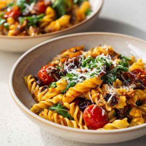 Bowl of vegan pasta with creamy sauce and fresh vegetables