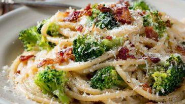 Creamy bucatini pasta tossed with melted cheese, crispy maple bacon, and tender broccoli florets served in a rustic bowl.