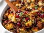 Cranberry sausage stuffing baked with bread cubes, savory sausage, tart cranberries, and fresh herbs served in a casserole dish.