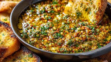Delicious loaded bread dipping oil made with olive oil, garlic, herbs, and spices, served with crusty bread.