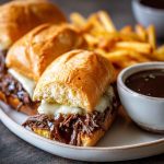 Slow cooker French dip sandwiches with tender beef, melted cheese, and toasted hoagie rolls served with au jus dipping sauce.