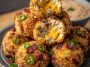 Bacon jalapeño popper cheese balls coated in crispy bacon bits, filled with creamy cheese and spicy jalapeños, served on a party platter.
