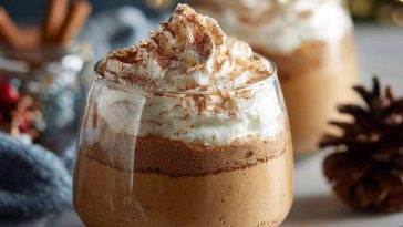 Creamy gingerbread latte mousse topped with whipped cream, dusted with cinnamon, and garnished with gingerbread cookie crumbs.