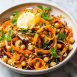 Bright Moroccan carrot and chickpea salad with fresh herbs, citrus dressing, and colorful toppings served in a rustic bowl.