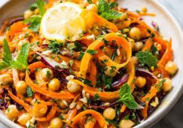 Bright Moroccan carrot and chickpea salad with fresh herbs, citrus dressing, and colorful toppings served in a rustic bowl.