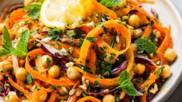 Bright Moroccan carrot and chickpea salad with fresh herbs, citrus dressing, and colorful toppings served in a rustic bowl.