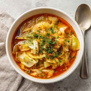 "A bowl of homemade cabbage fat burning soup with fresh vegetables, herbs, and a light broth."